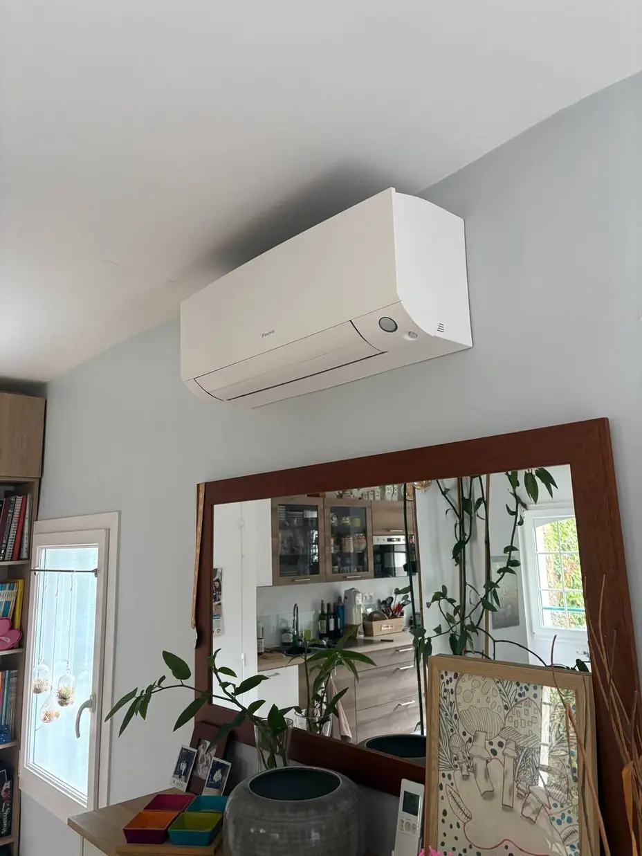 Climatiseur mural Daikin posé au-dessus d'un grand miroir dans le séjour d'une maison à Clamart (92)