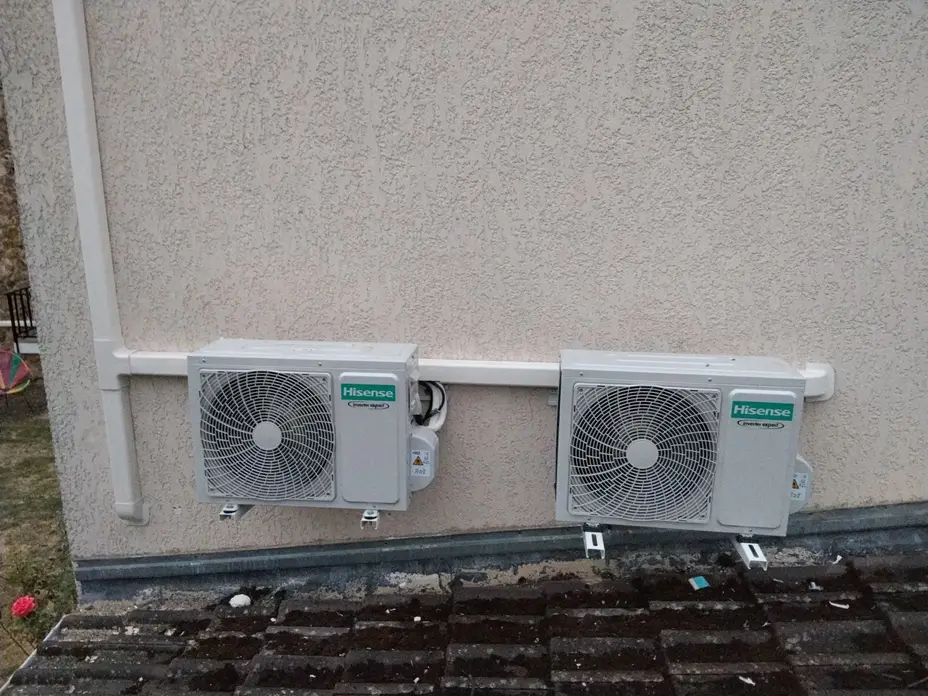 Deux groupes extérieurs Hisense fixés en façade au-dessus d'une toiture, liaisons sous goulotte, Épône (78)