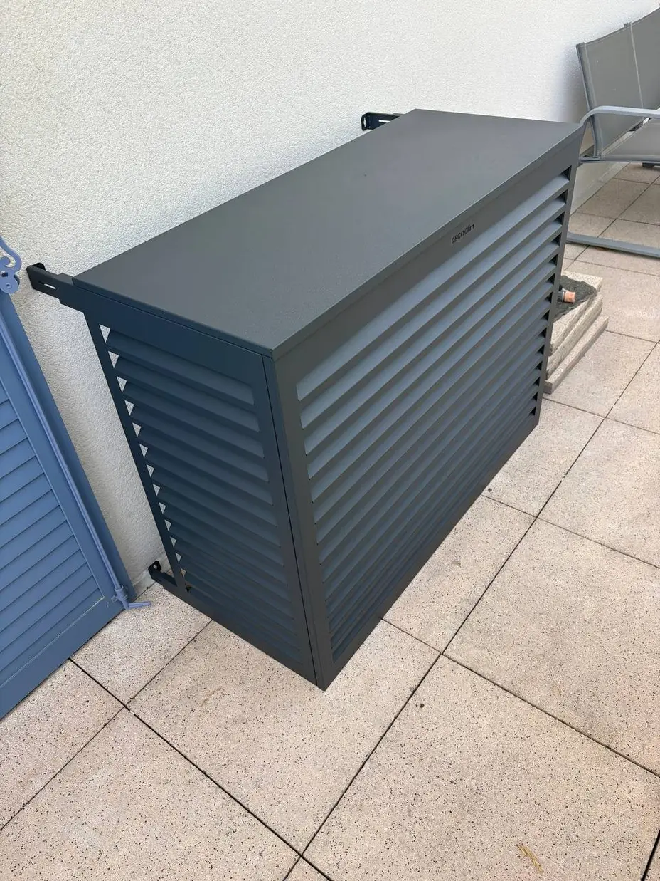 Cache décoratif à claustras métalliques habillant un groupe extérieur de climatisation sur un balcon, Évry-Courcouronnes (91)