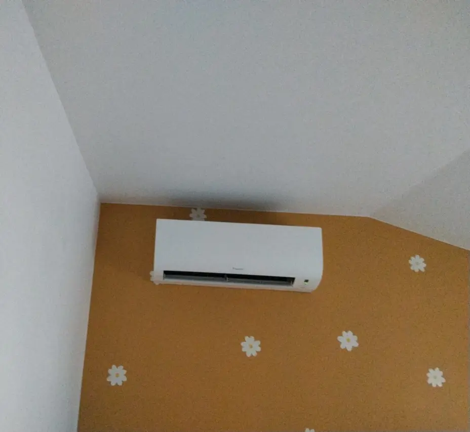 Unité murale Daikin FTXP20N9 posée au-dessus d'un mur à motifs floraux dans une chambre d'enfant, Gargenville (78)