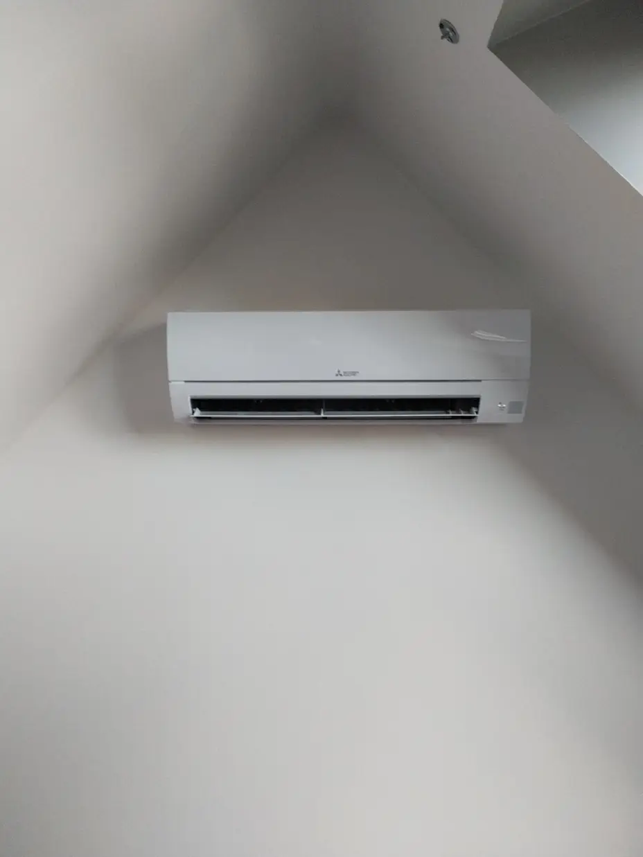 Climatiseur mural Mitsubishi Electric posé sous rampant dans un salon à Neauphlette (78)