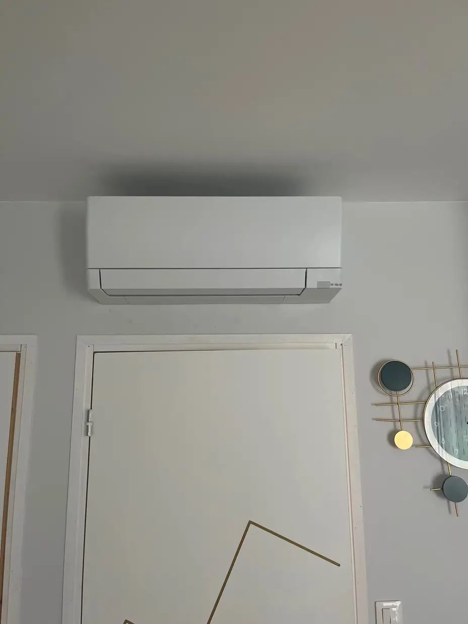 Climatisation réversible Mitsubishi Electric installée au-dessus d'une porte à Chambourcy (78)